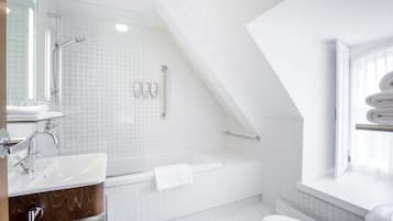 A modern bathroom with a white sink, vanity, bathtub, and toilet.