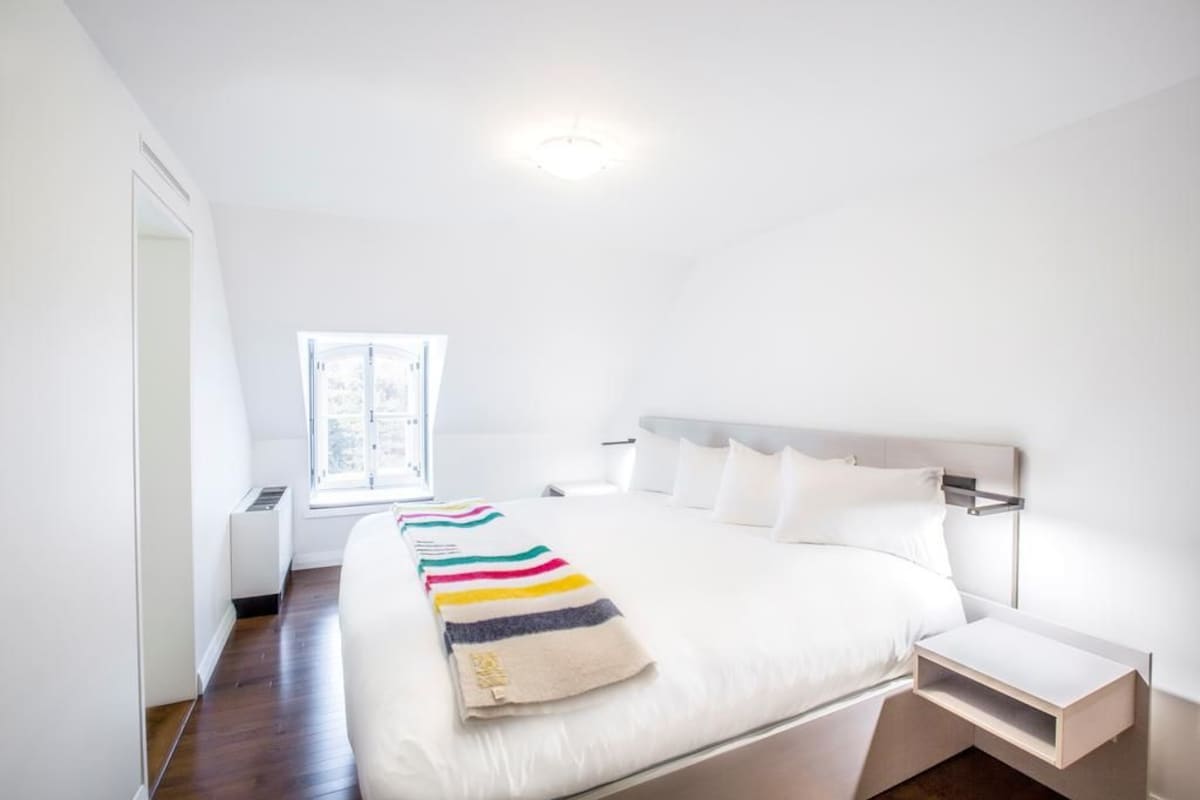 Ein modernes Schlafzimmer mit einem großen Bett, einem Nachttisch, einem Fenster und einer Heizung.