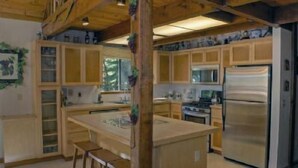 A kitchen with wooden cabinets, a central island, and a stainless steel refrigerator. - St. Croix (Truckee)