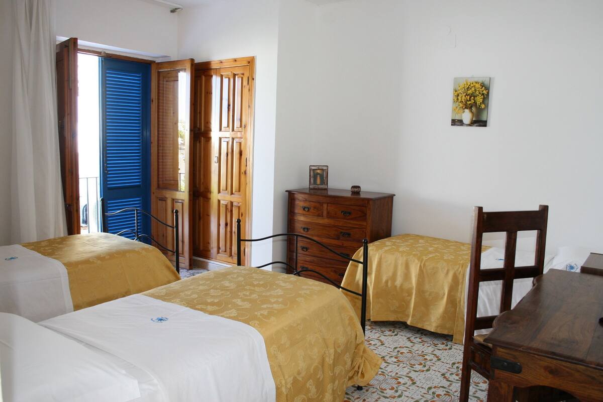 A room with two beds, a wooden dresser, a chair, and a small table.