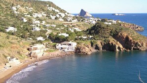 A coastal village with white buildings, a rocky coastline, and a clear view of the sea. - Hotel Tesoriero (Panarea)