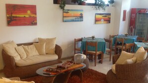 A living room with a sofa, two wicker chairs, a coffee table, and a dining area with a table and chairs. - Hotel Tesoriero (Panarea)