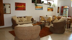 A living room with a sofa, armchairs, a dining table with chairs, and a refrigerator. - Hotel Tesoriero (Panarea)