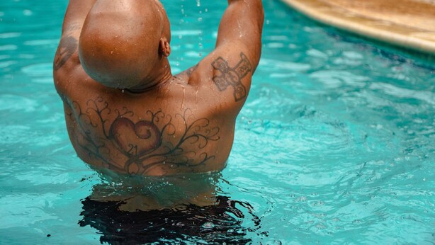 Un homme soulève un enfant au-dessus d’une piscine, et l’eau éclabousse tout autour.