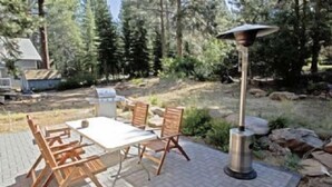 Eine möblierte Terrasse im Freien mit Tisch, Stühlen, Grill und Laterne.