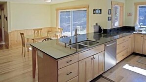 Eine moderne Küche mit Holzausbau, einem Edelstahl-Spülbecken und einem Essbereich mit Holztisch und Stühlen.