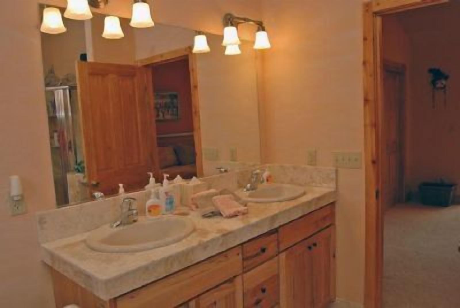A bathroom with two sinks, wooden cabinets, and a large mirror.
