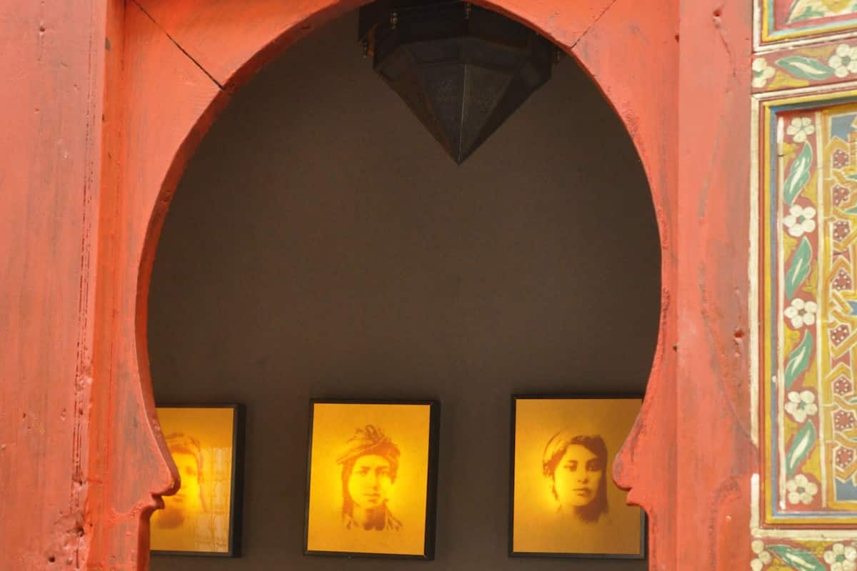 An arched doorway with three framed portraits on the wall.