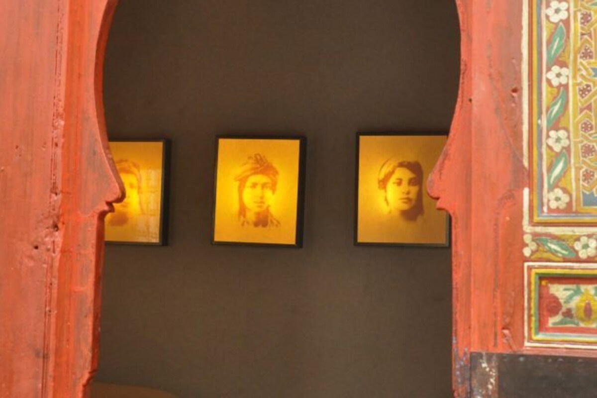 A wall with three framed portraits illuminated by warm lighting.