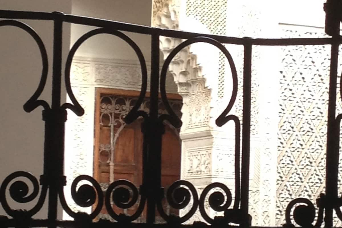 A view through ornate iron railings of a building's interior with detailed architectural elements and a wooden door.