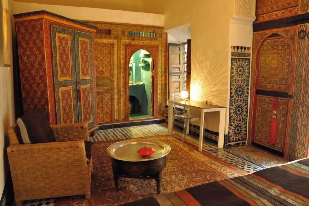 A traditional interior with ornate doors, a patterned carpet, and wicker furniture.