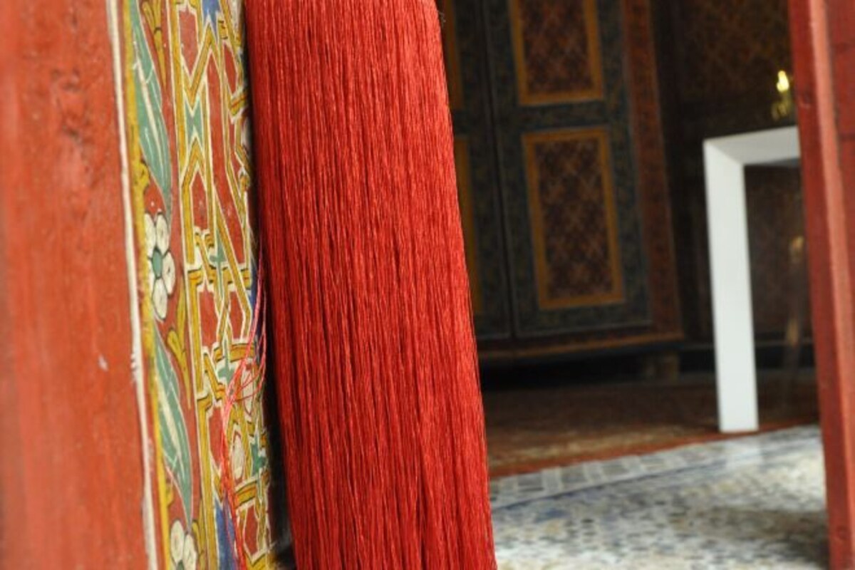 A close-up of a red carpet leading to a room with ornate, colorful wall designs.