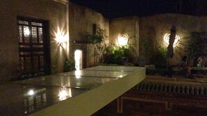 Un patio con un estanque reflectante, paredes de piedra e iluminación tradicional.