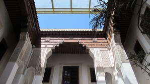 Un patio interior con arcos ornamentales y vista al cielo a través de un techo de cristal.