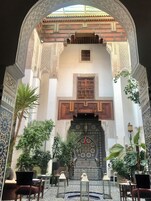 Pátio interno com trabalhos intrincados em azulejos, uma fonte central e áreas de estar.