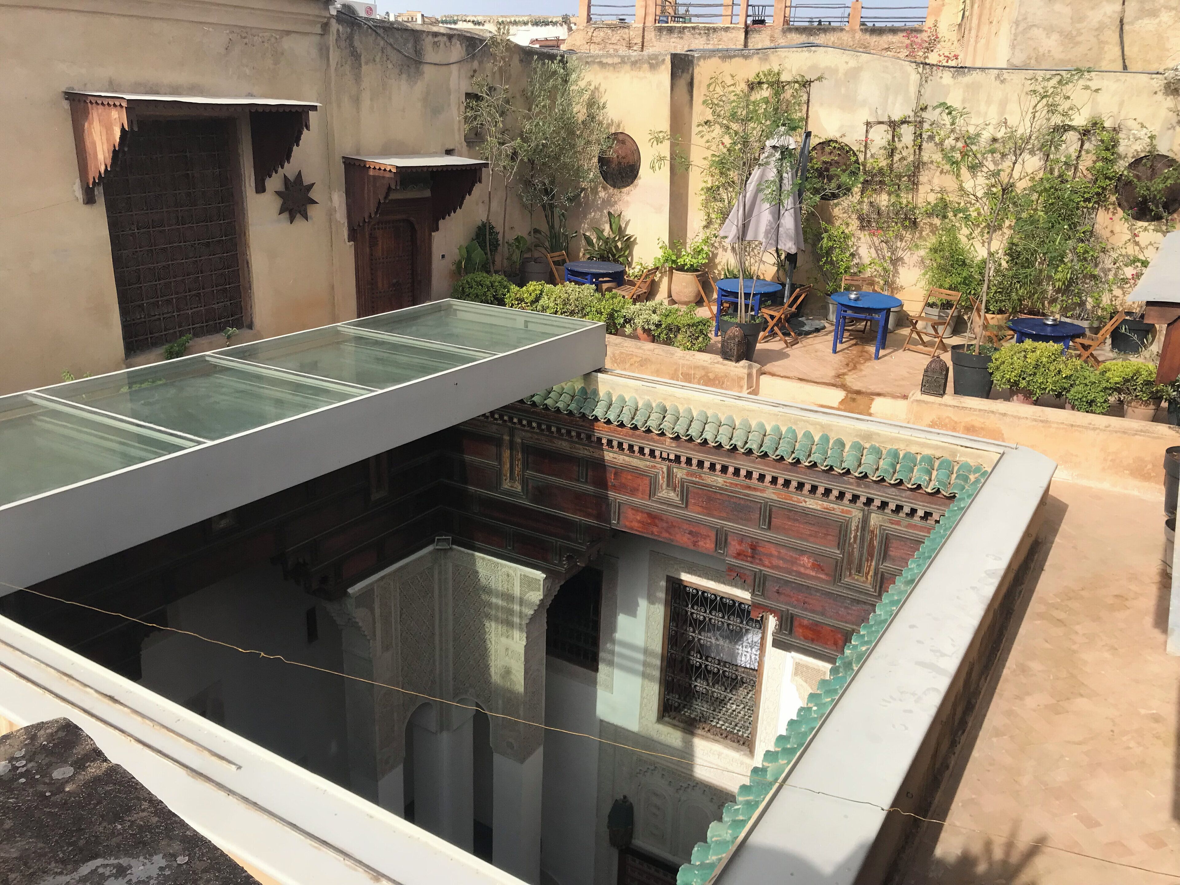 A rooftop terrace with a glass viewing platform, potted plants, and traditional architectural elements.