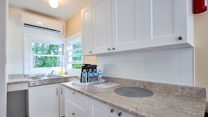 A kitchen with white cabinets, a built-in stove, a window, and a water dispenser. - Hollywood Cottages (Wasaga Beach)
