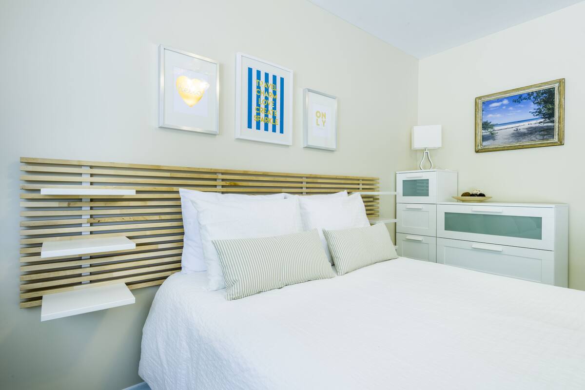 A neatly arranged bedroom with a bed, bedside tables, and a TV.