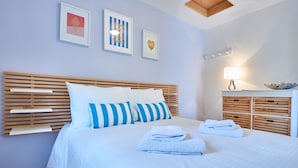 A neatly made bed with blue and white striped pillows, a wooden headboard, and a bedside table with a lamp and decorative items. - Hollywood Cottages (Wasaga Beach)