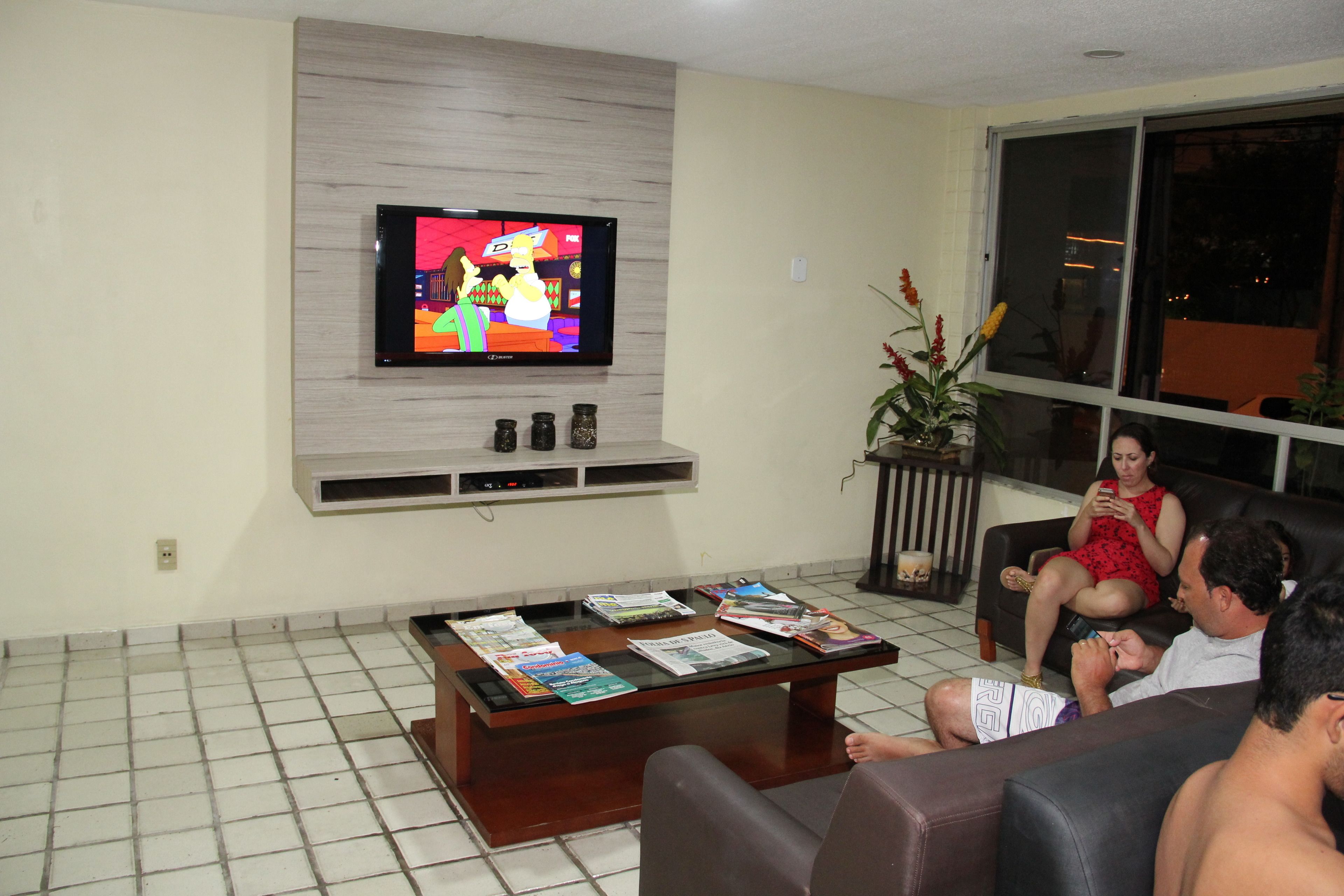 Una sala de estar con televisor, una mesa de centro con revistas y un sofá.