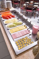 Buffet com diversos alimentos e utensílios.