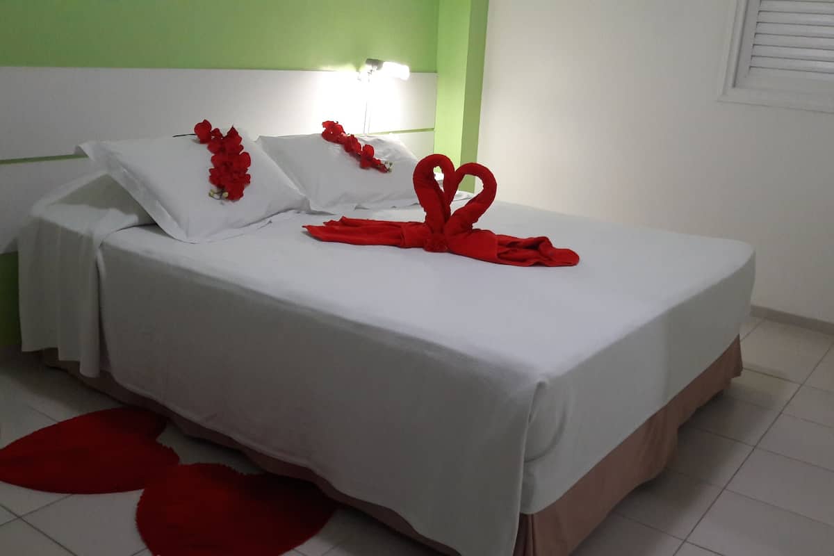 Een hotelkamer met een bed, wit beddengoed en rode decoraties.