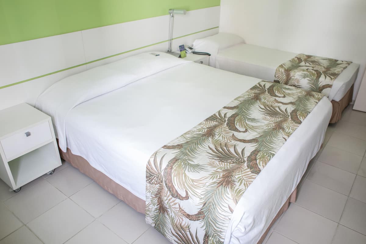 Een hotelkamer met een groot bed, een nachtkastje en een bedtafel.