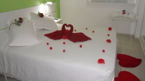Une chambre d’hôtel avec un lit, une table de chevet, une lampe et une fenêtre avec des rideaux.