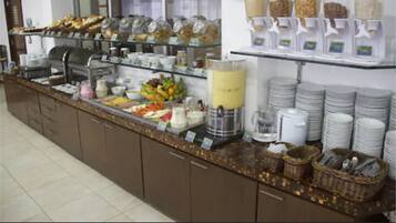 A buffet area with various food items, a coffee station, and stacked plates.