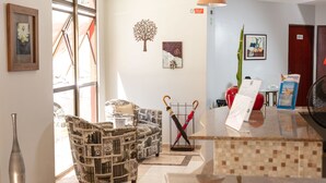 A reception area with a patterned armchair, a standing umbrella, and a reception desk. - Hotel Ciribaí (Maceió)