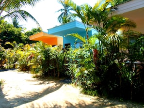 Un resort tropical con un sendero de tierra que lleva a un edificio de fachada azul y naranja.