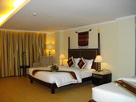 Una habitación de hotel con dos camas, una silla, una mesita de noche y una lámpara.
