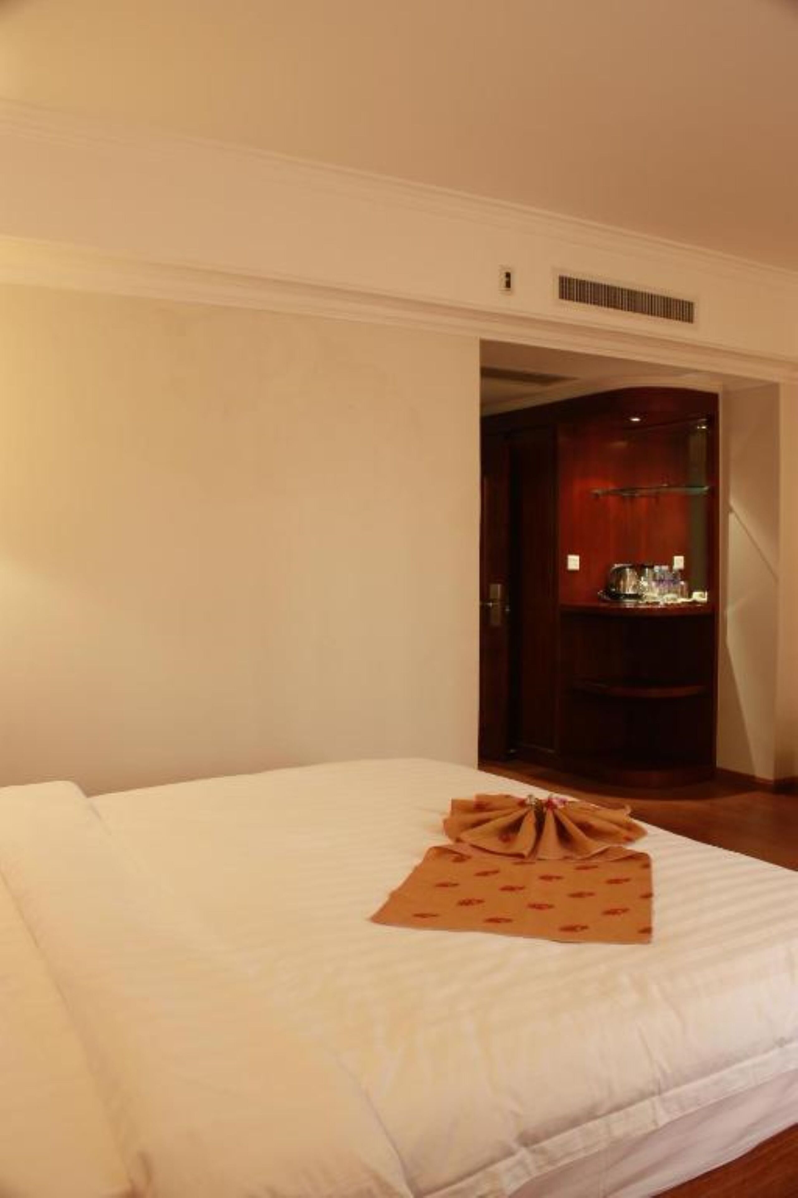 Una habitación de hotel con una cama bien hecha, un armario de madera y un espejo.