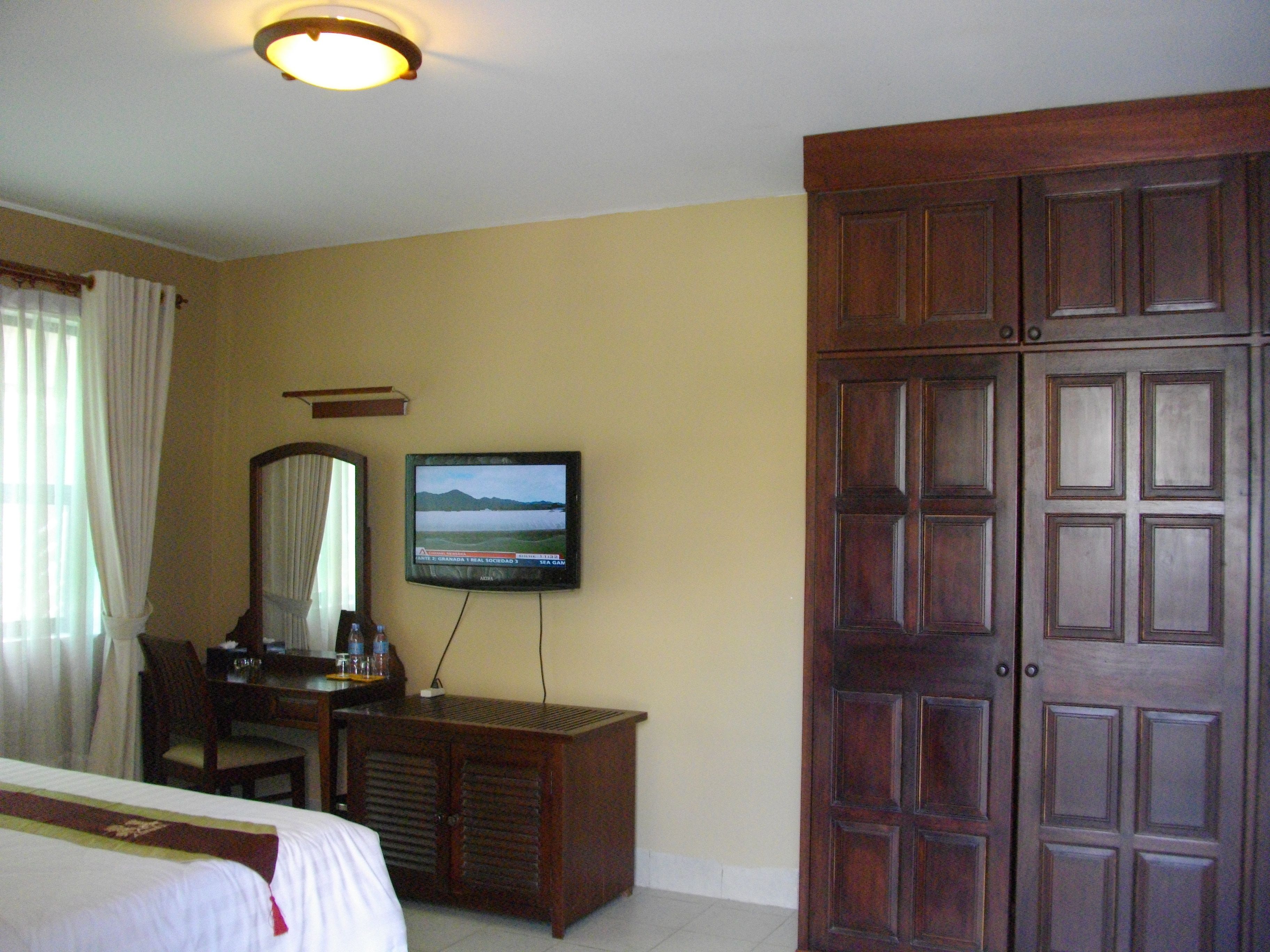 Een hotelkamer met een bed, een bureau, een televisie en een kledingkast.