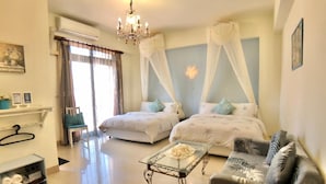 Ein Schlafzimmer mit zwei Betten, einem Schlafsofa, einem Glastisch und einem Kronleuchter.