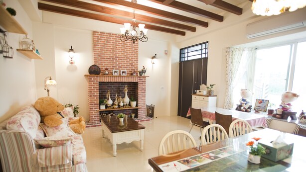 A cozy living room with a brick fireplace, a dining table, and a sofa. - Blue Cotton Candy (Taitung)