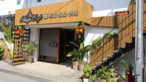 A cafe with a wooden facade, outdoor seating with potted plants, and a staircase leading to the entrance. - Romeo B&B (Taitung)