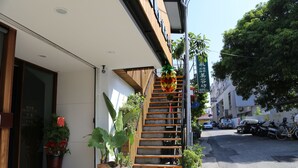 A building with a wooden staircase leading to a second floor, potted plants, and a clear sky. - Romeo B&B (Taitung)