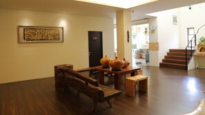 A spacious living area with a wooden bench, a table with decorative vases, and a staircase leading to another level. - Romeo B&B (Taitung)