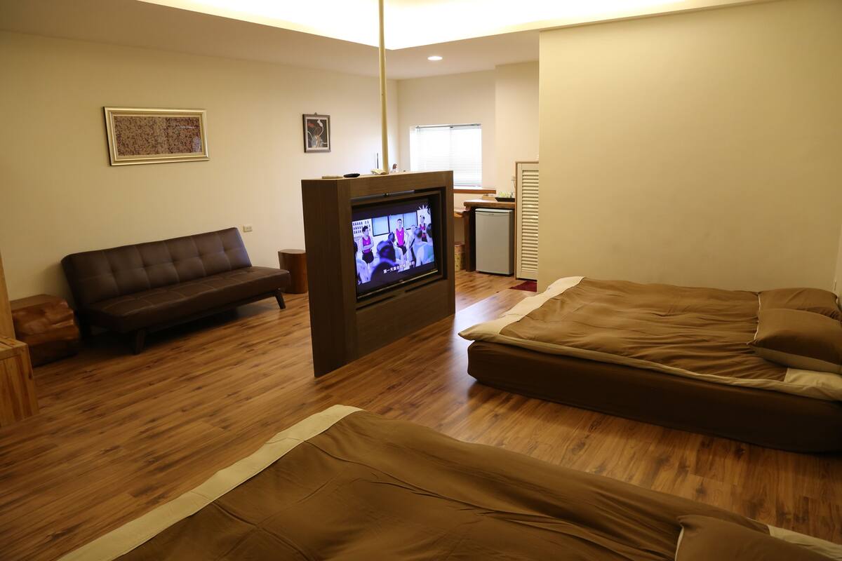 A living room with a sofa, a TV, and a bed.