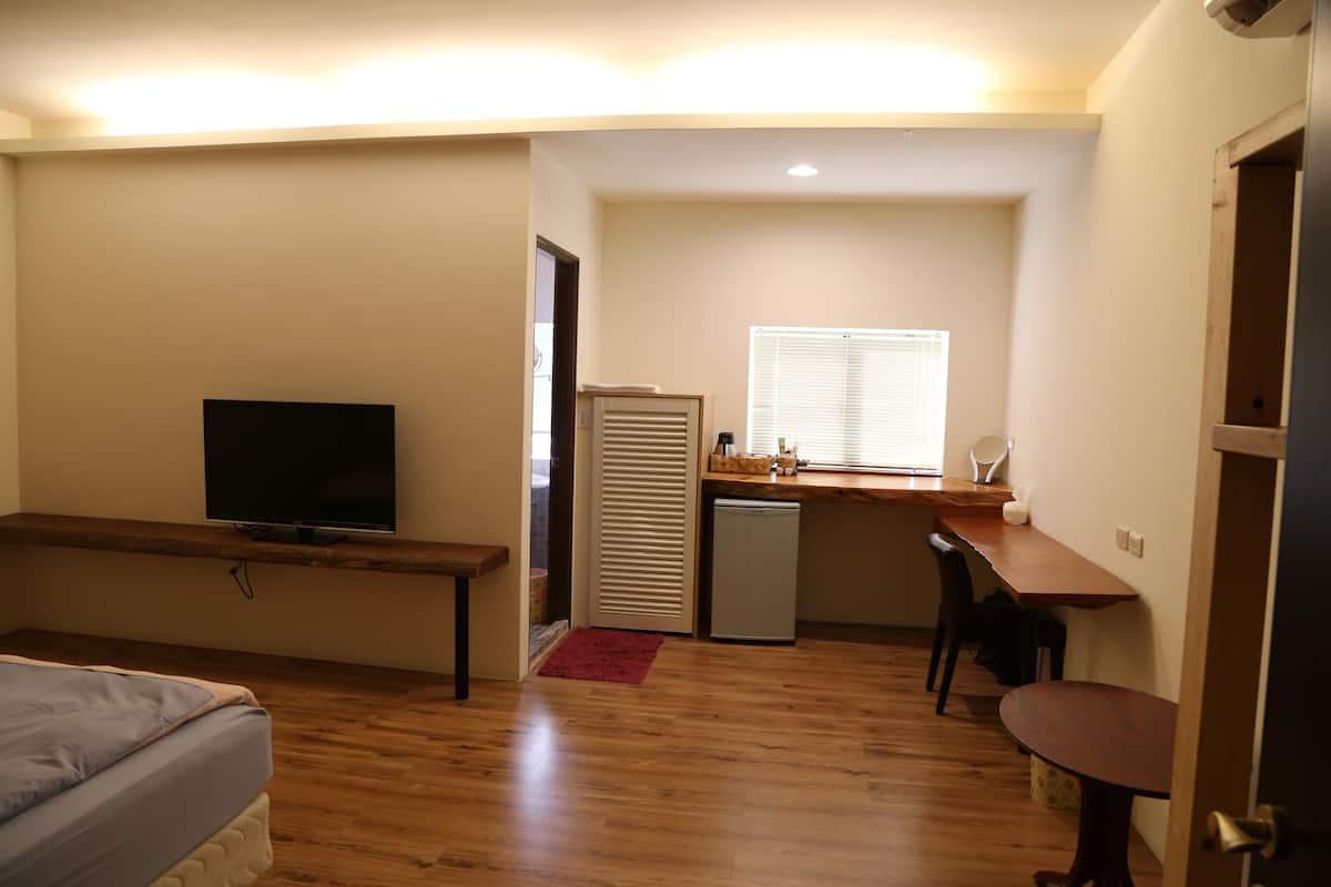 A compact room with a bed, a TV, a small kitchenette, and a dining area.