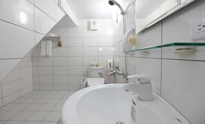A modern bathroom with a white sink, a glass shower enclosure, and a toilet.