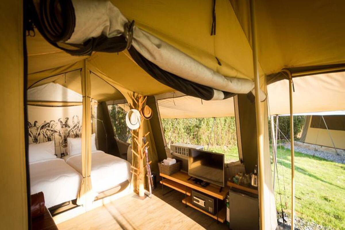 Een tentaccommodatie met twee bedden, een televisie en een kleine tafel.