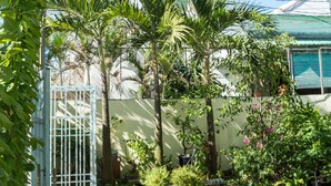 A courtyard with a tiled floor, potted plants, and a metal gate. - Areca Homestay (Da Nang)