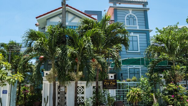 A building with a blue facade, a white gate, and various potted plants. - Areca Homestay (Da Nang)