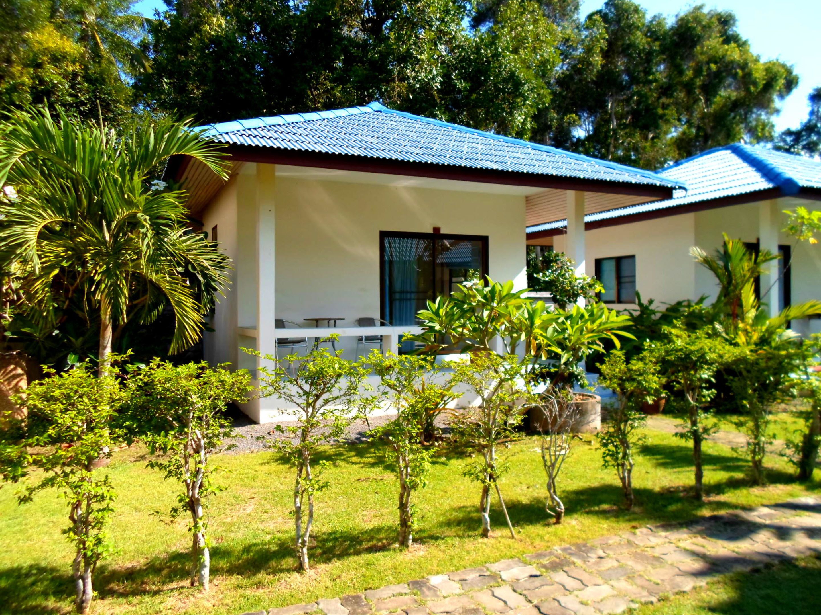 A two-story building with a blue roof, surrounded by well-maintained greenery and a stone pathway.