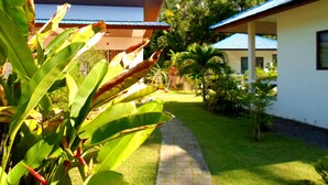 A pathway leading to a building with a blue roof, surrounded by lush greenery and palm trees. - Baan Kuasakul Resort (Koh Samui)