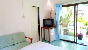A hotel room with a bed, a small TV on a stand, a desk with a computer, and a sliding glass door to a balcony. - Baan Kuasakul Resort (Koh Samui)