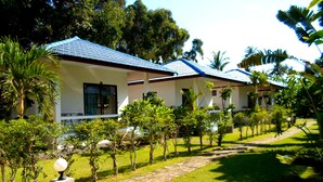 A row of white buildings with blue roofs, surrounded by well-maintained greenery and a stone pathway. - Baan Kuasakul Resort (Koh Samui)