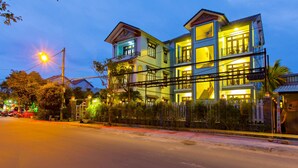 A multi-story building with balconies and a well-lit facade at dusk. - Magnolia Garden Villa (Da Nang)